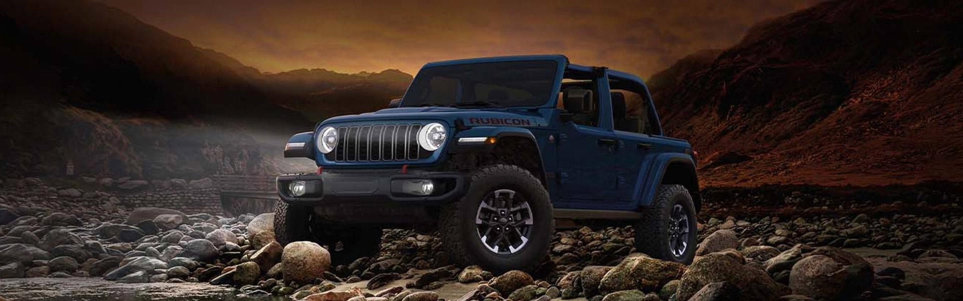 2026 Jeep Wrangler off-road SUV tackling rocky terrain at sunset, highlighting extreme trail performance, 4x4 capability, durable build, and adventure-ready versatility.