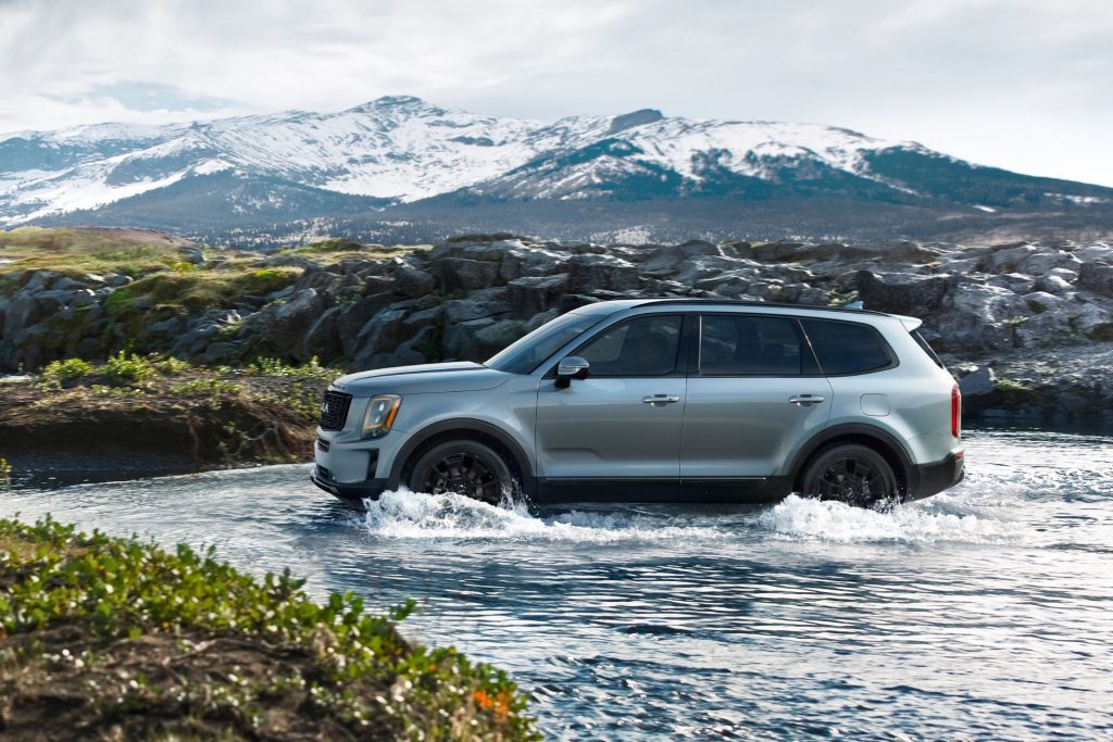Kia telluride riding in water flow in the mountain area.