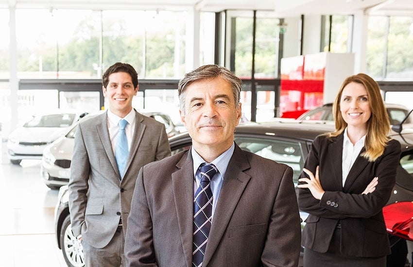 Automotive sales team standing inside a showroom.
